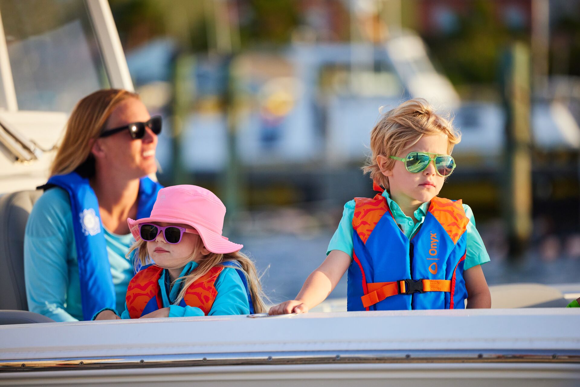 A woman and two children in life jackets on a boat.