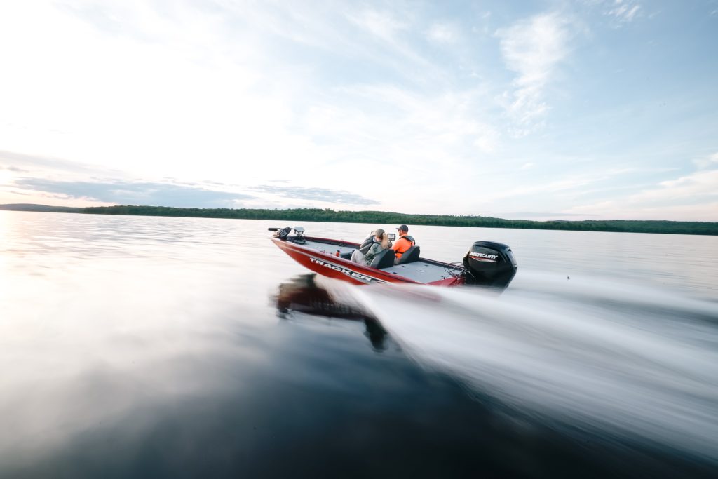 A red fishing boat moves quickly on the water, know Florida life jacket laws concept.