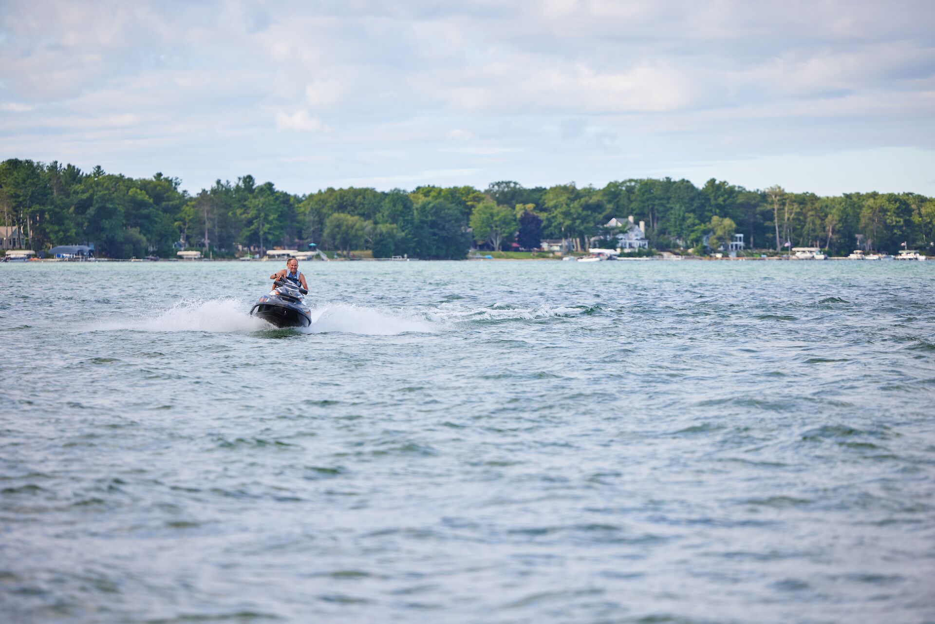 Riders on a personal watercraft (PWC) on a lake.