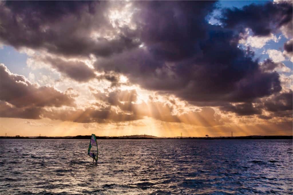A person kite surfing in the distance on a lake.