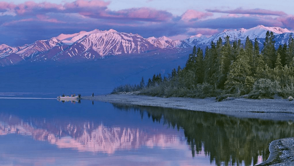 A wide view of a lake with trees and mountains in the background, boating in Canada concept.