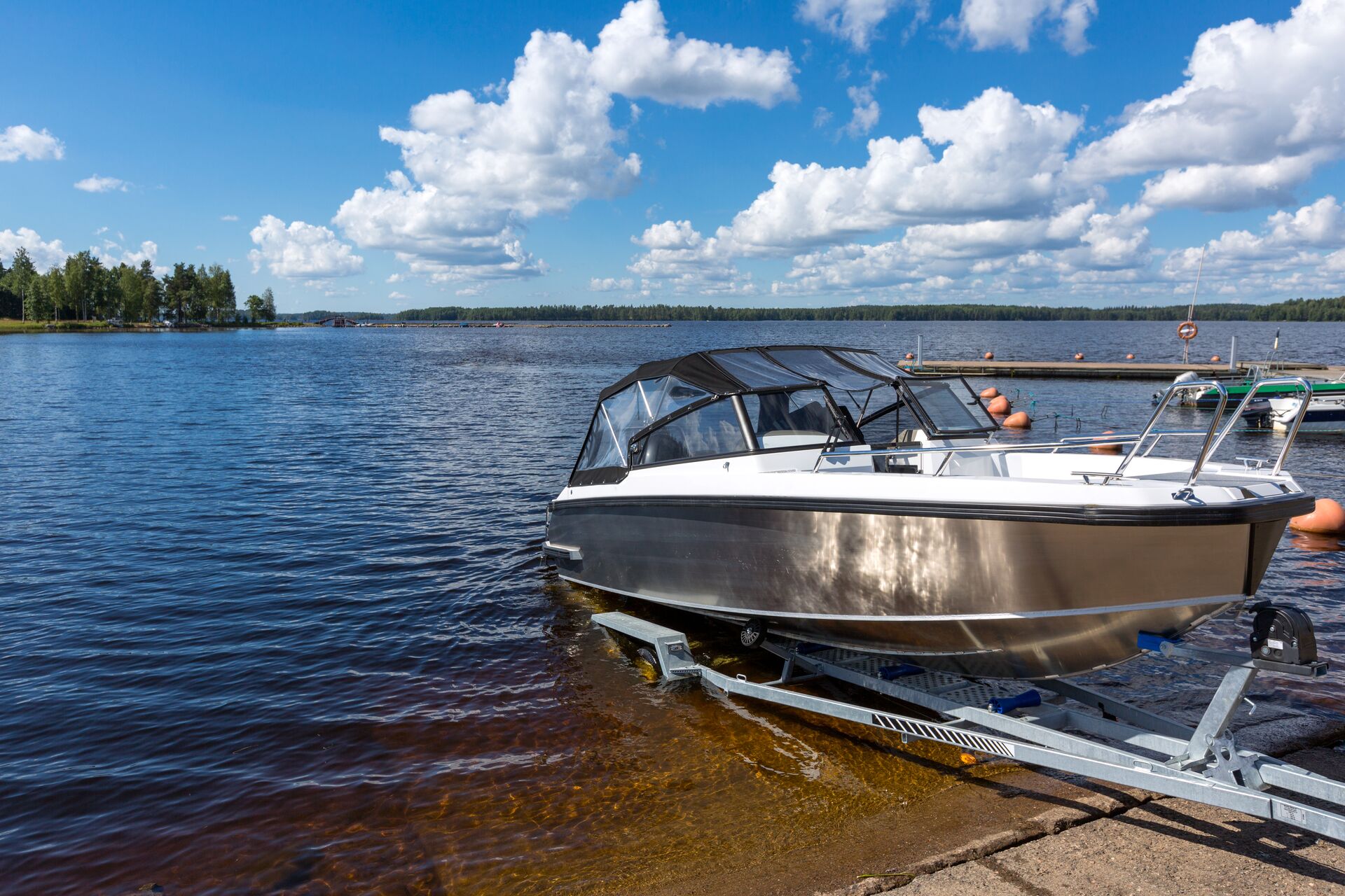 A boat on a trailer launching into a lake.