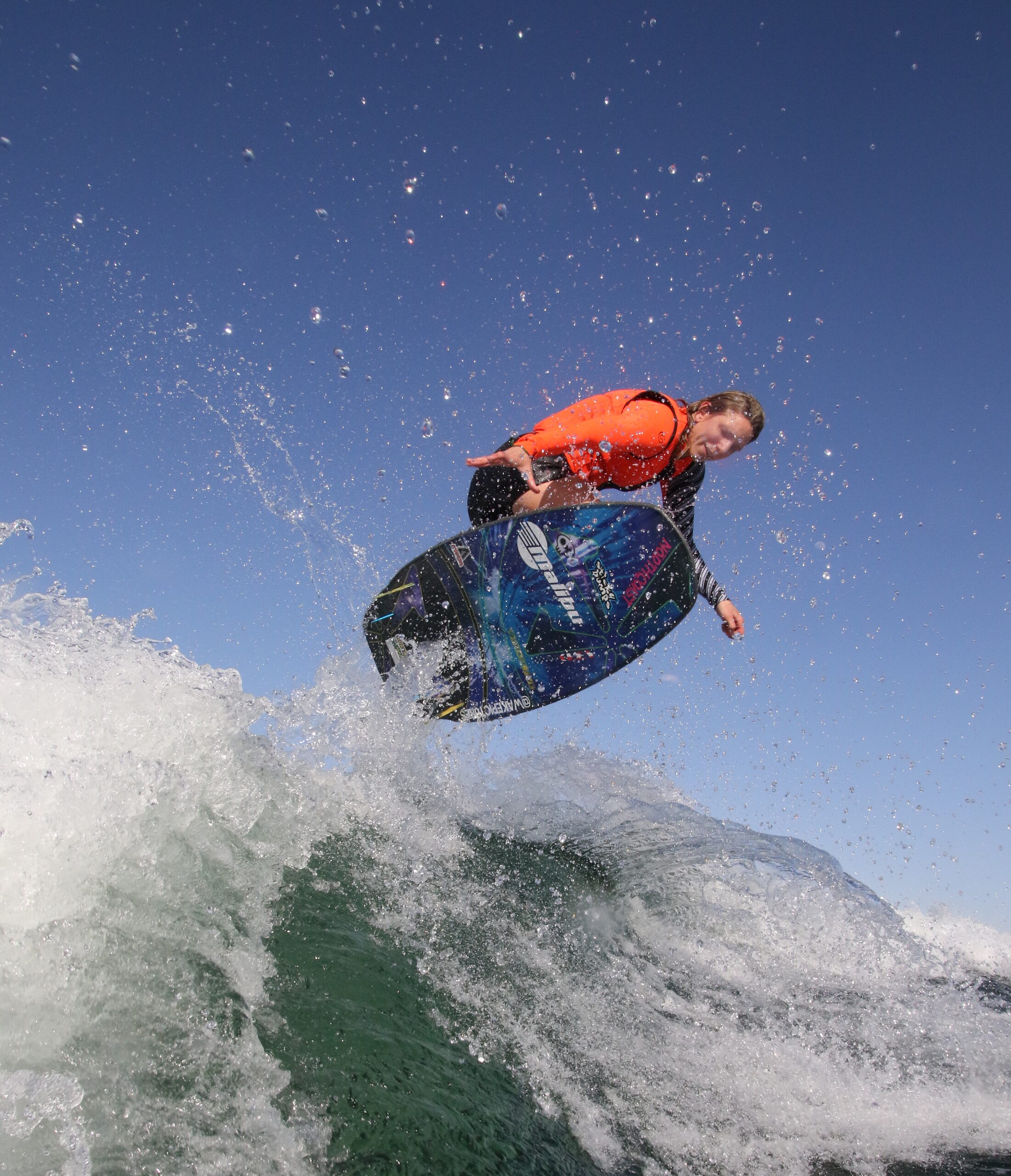 A man on a wakeboard at the top of a wake, extended boating season concept.
