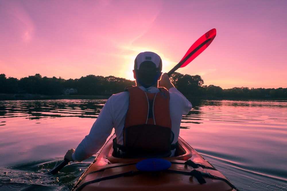 A guy kayaking on calm water.