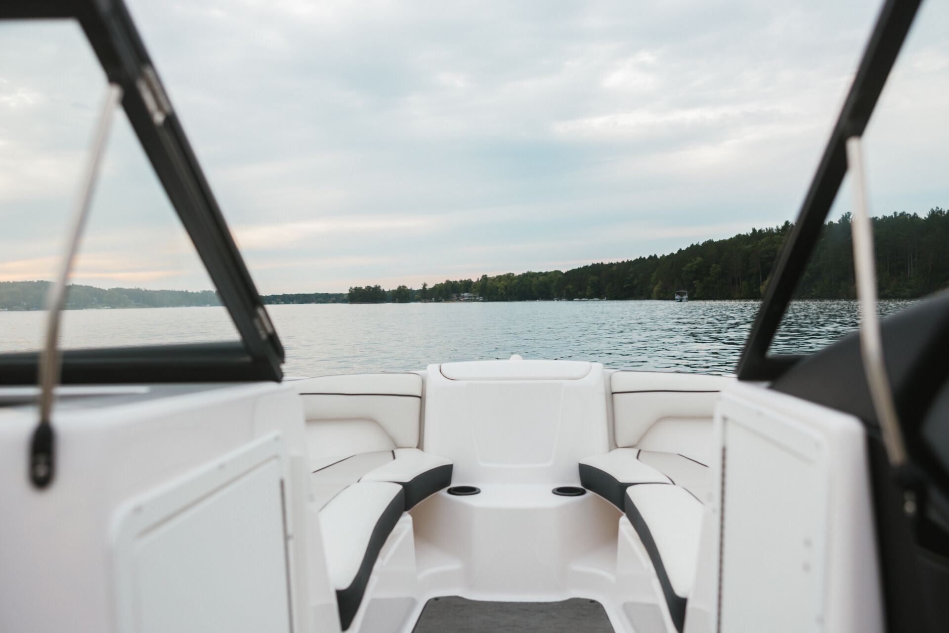The view of a lake and trees from the back of a boat.
