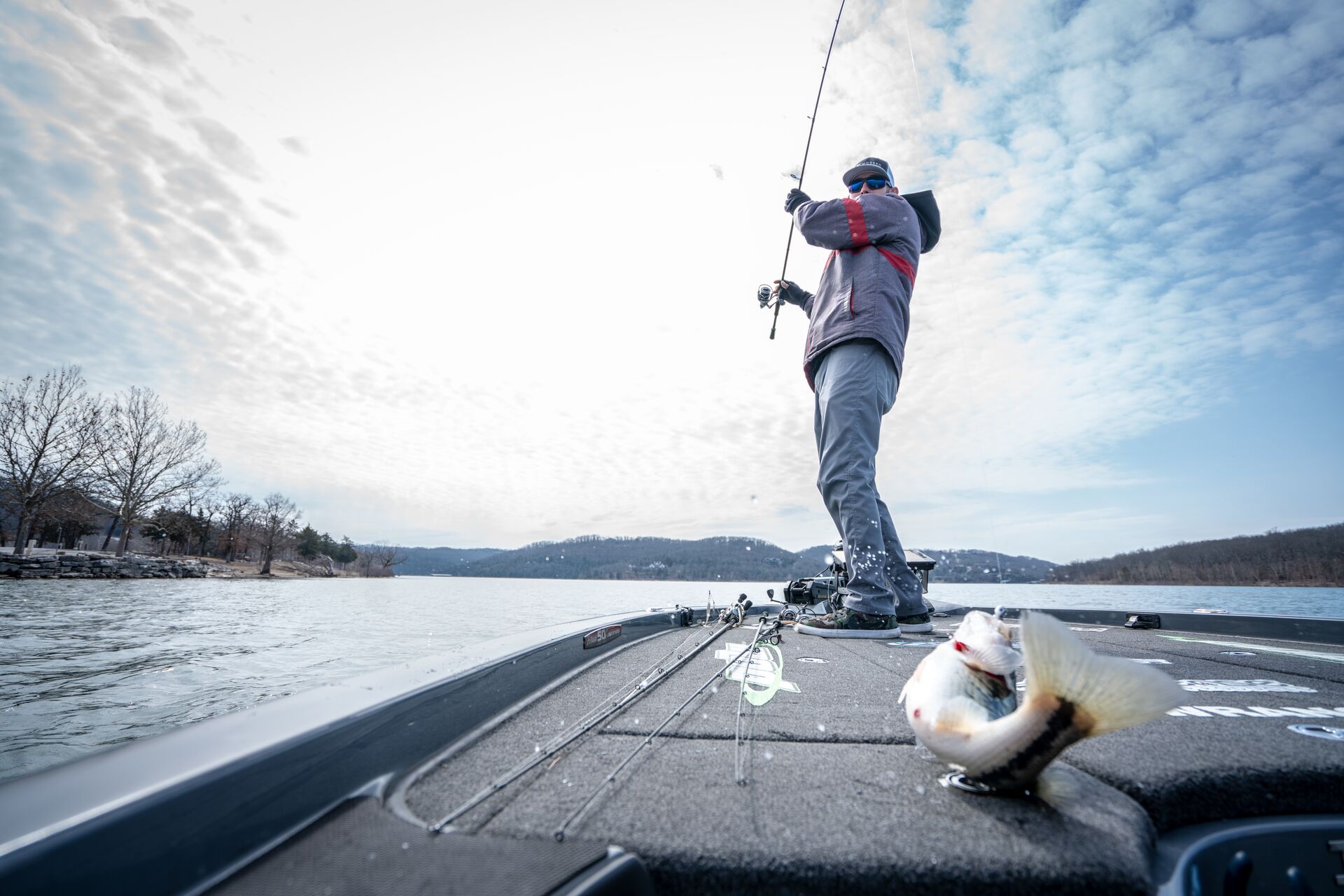 A man pulls a fish onto a boat.
