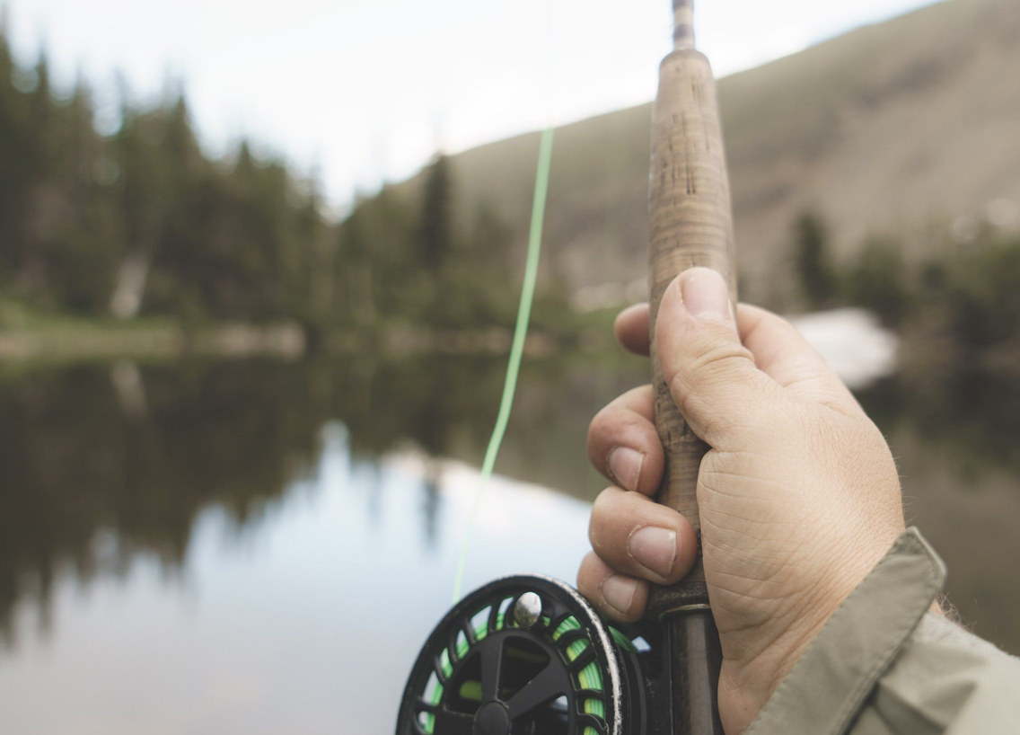 Close-up of a hand holding a fishing rod at a lake, fishing and boating in Washington concept.