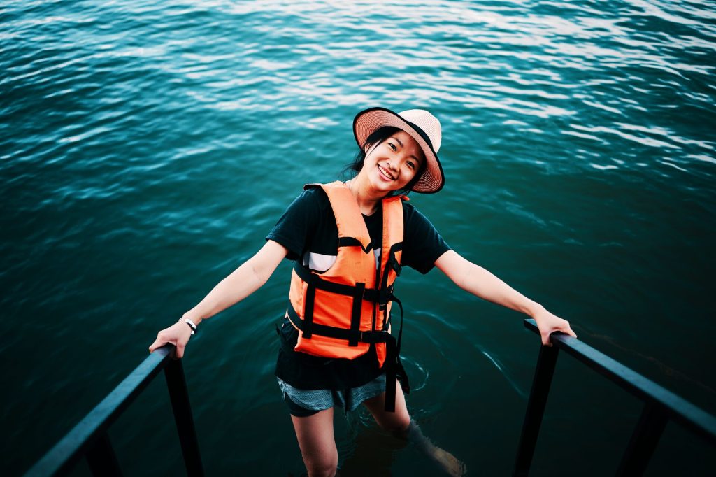 A happy woman standing in water wearing a life jacket, gifts for the boater concept.