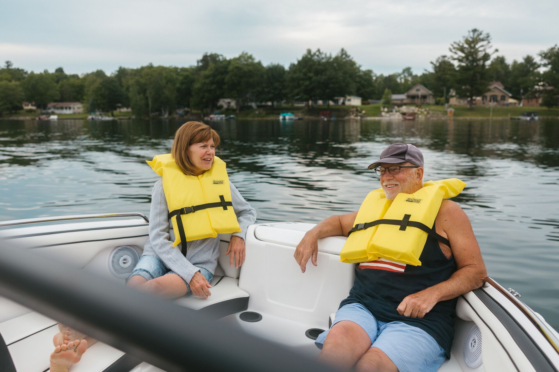 Two people relaxing in a boat while wearing life jackets, boating in New Brunswick concept.
