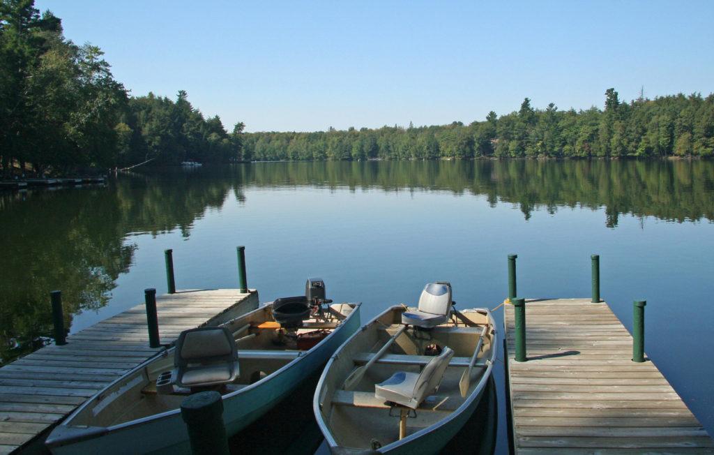 Two empty boats at docks on a lake. 