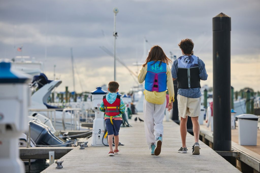 Kids walking on a dock wearing life jackets, Florida life jacket law concept.