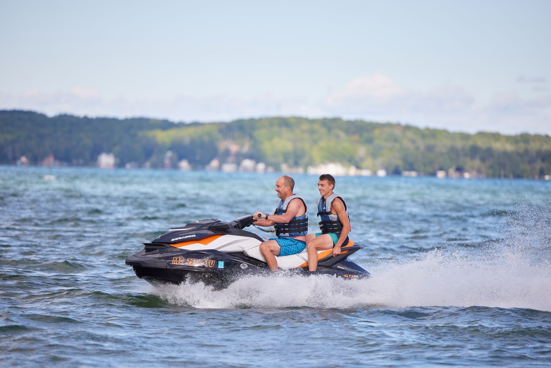 Two guys riding a personal watercraft with a kill-switch for safety.
