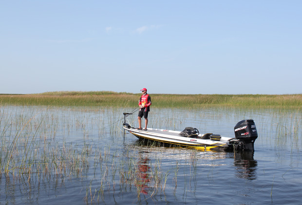 A man standing in a fishing boat with a line in the water, boating on lake Okeechobee concept.