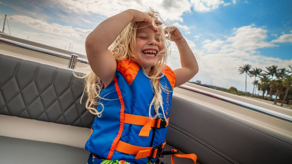 A child wearing a life jacket in a boat while smiling