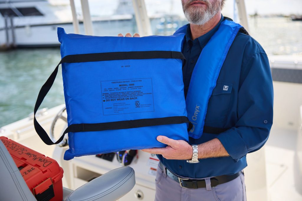 A man holds a throwable PFD on a boat, boat safety equipment concept.