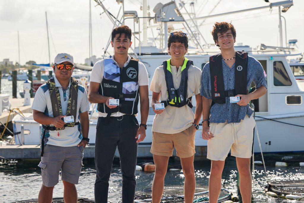 Four men holding boat license cards, learn about boat safety through a boater course concept.