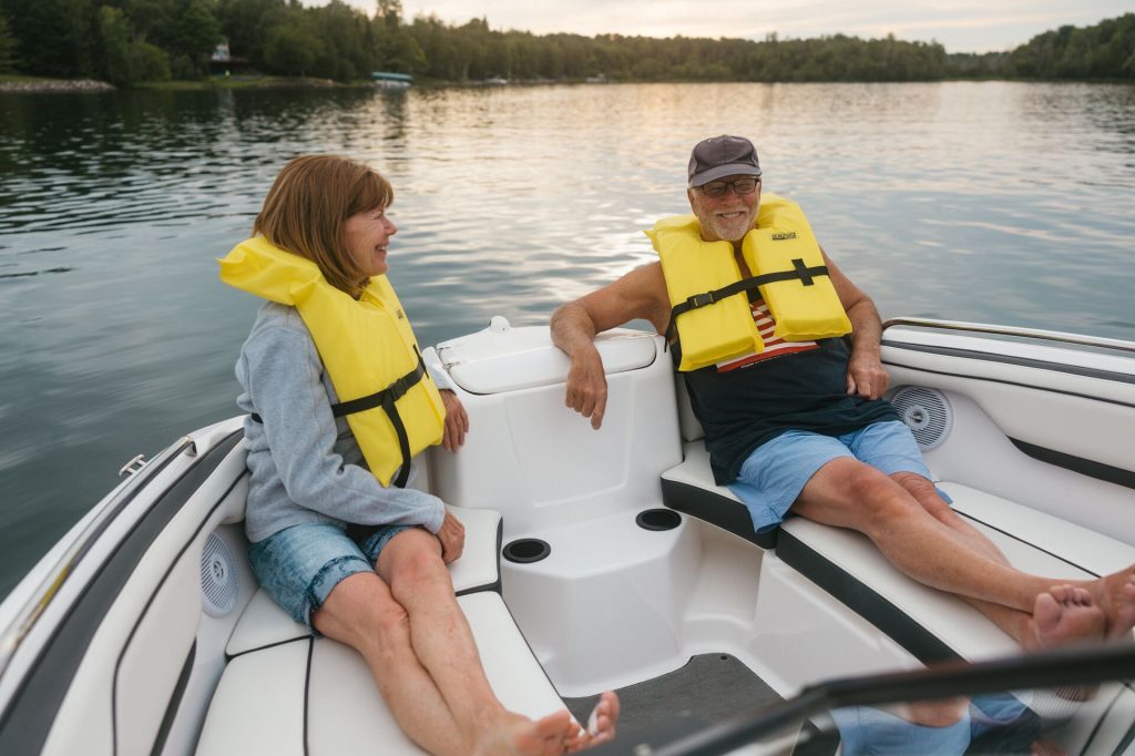 An older man and woman wearing yellow lifejackets on a boat, boating safety concept.