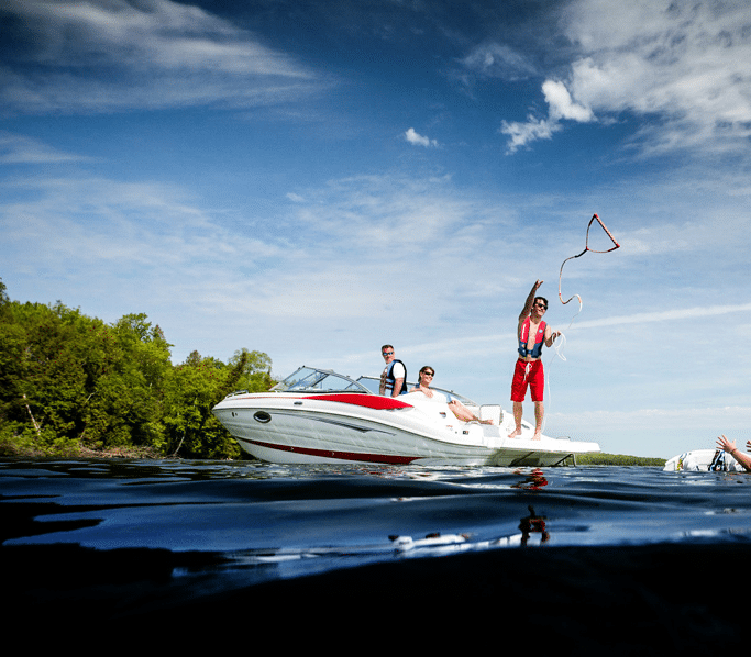 A person on a boat tosses a line to a water skier